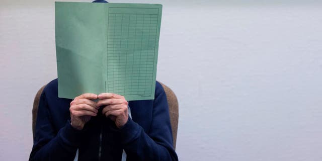 The defendant in the Wermelskirchen abuse complex holds a folder in front of his face in the courtroom in Cologne, Tuesday, Feb. 28, 2023. 