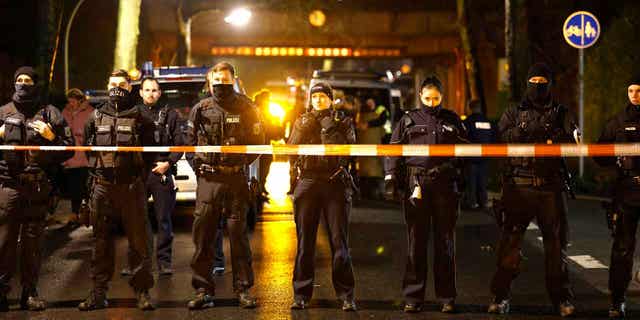 Police officers stand at a barrier near the train accident site in Recklinghausen, Germany, on Feb. 2, 2023. One child was killed, and another was seriously injured in the accident.