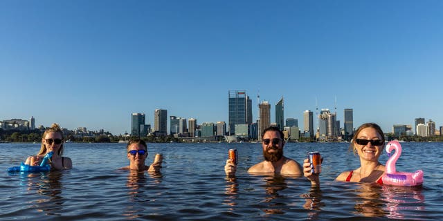 Sarah Jackson, Sam Rowe, Lachlan Alexander and Monica Lewis enjoy a drink and swim in the Swan River at South Perth on January 22, 2022 in Perth, Australia. 