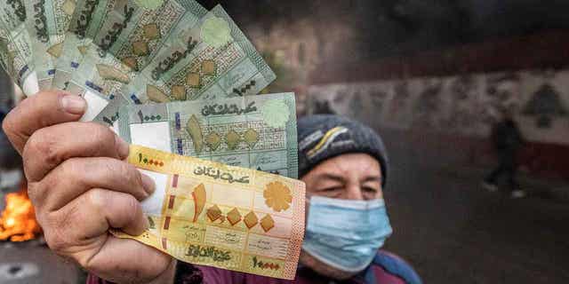 Lebanese pounds are shown in front of burning tires, in front of the country's Central Bank building, where the anti-government demonstrators rally against the Lebanese Central Bank Governor Riad Salameh.
