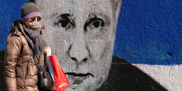 A woman passes by a mural depicting the Russian President Vladimir Putin in Belgrade, Serbia, Saturday, March 12, 2022.