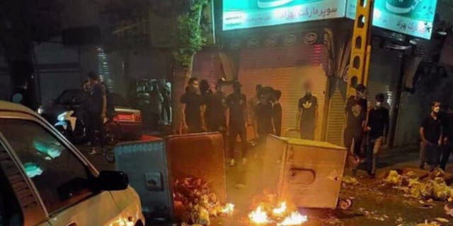 Protesters gather around burning rubble in the streets of Iran. 