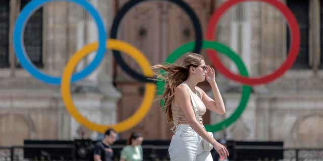 A woman passes by the Olympic rings, at the City Hall in Paris, on July 25, 2022. Latvia is threatening to boycott the 2024 Olympics in Paris if Russian athletes are allowed to compete.