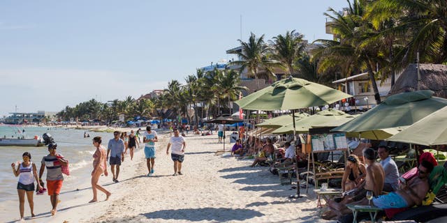 Tourists walk on a beach in Playa del Carmen, Mexico, on Tuesday, July 11, 2017.