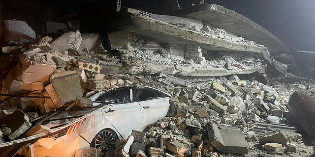 A car is seen under the wreckage of a collapsed building, in Azmarin town, in Idlib province, northern Syria.