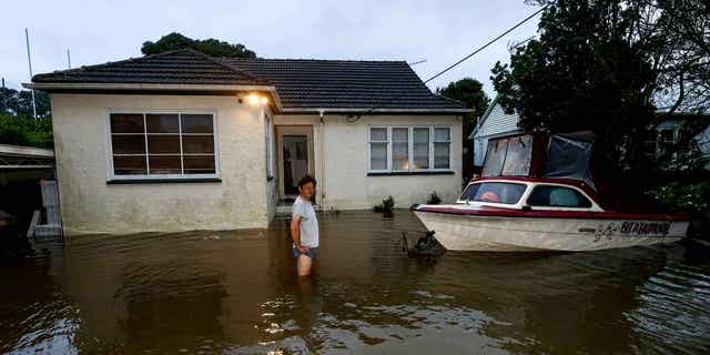 A man stands in knee-deep water outside his house in Auckland, New Zealand, on Feb. 1, 2023. Auckland lifted a state of emergency declaration after the storm didn't turn out as bad as feared on Wednesday.