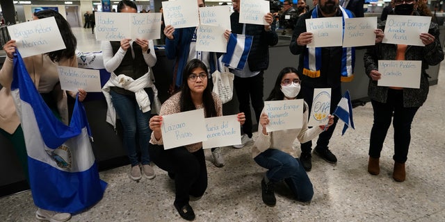 Activists hold up signs with the names of some of the more than 200 political prisoners released from Nicaragua, as they await their arrival at Dulles International Airport in Virginia outside Washington, D.C., February 9, 2023. 
