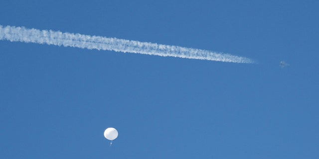 FILE PHOTO: A jet flies by a suspected Chinese spy balloon as it floats off the coast in Surfside Beach, South Carolina, U.S. February 4, 2023.  