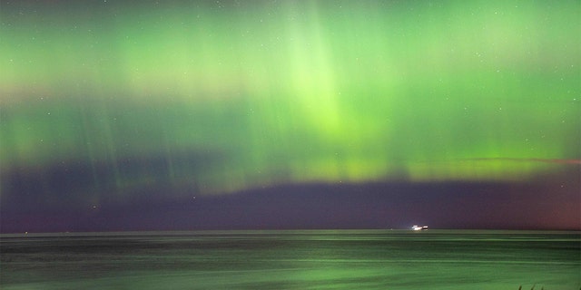 Northern lights (aurora borealis) illuminate the sky as visitors walk along Hornbaek Beach in the northern part of Sealand, Denmark, late on Feb. 27, 2023.
