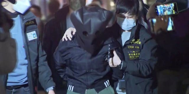 Police officers escort a 47-year-old suspect in connection with the killing of 28-year-old model Abby Choi, in Hong Kong Feb. 26, 2023 in this screenshot taken from a video. 