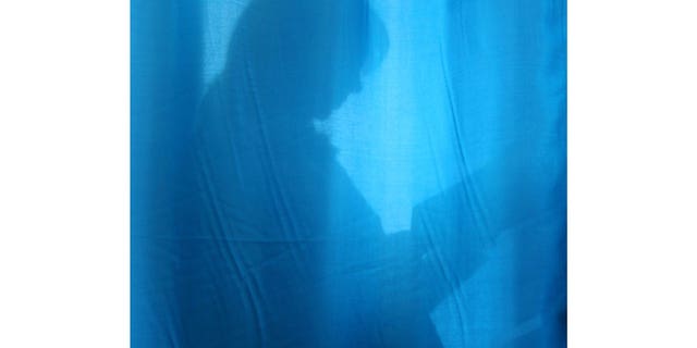 A pregnant woman is seen through the curtain at a maternity hospital in the Ukrainian capital Kyiv, on Oct. 31, 2004.