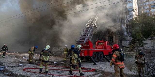 Firefighters help a local woman evacuate from a residential building destroyed by a Russian drone strike, which local authorities consider to be Iranian-made unmanned aerial vehicles (UAVs) Shahed-136, amid Russia's attack on Ukraine, in Kyiv, Ukraine October 17, 2022. 