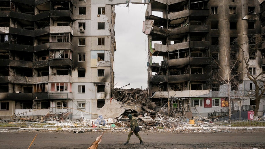 A Ukrainian serviceman walks by a destroyed Borodyanka apartment building