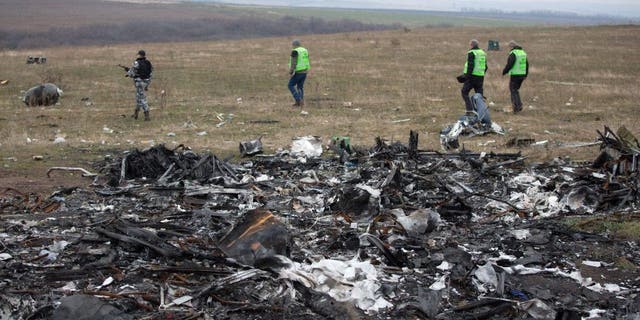 Dutch investigators accompanied by pro-Russian armed rebels arrive near parts of the Malaysia Airlines Flight MH17 at the crash site near the Grabove village in eastern Ukraine on Nov. 11, 2014.