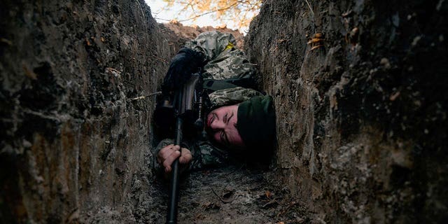 A Ukrainian soldier hides from a helicopter airstrike amid Russia's invasion of Ukraine, near Demydiv, Ukraine March 10, 2022. 