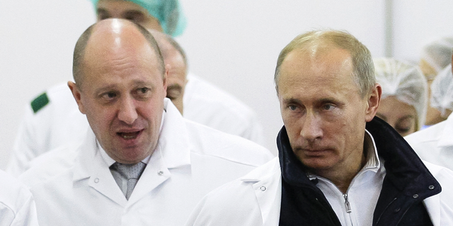 In this Sept. 20, 2010, photo, businessman Yevgeny Prigozhin, left, shows Russian President Vladimir Putin around his factory that produces school meals outside St. Petersburg, Russia. 
