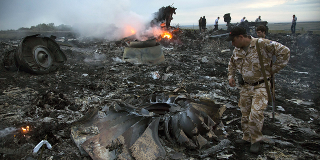 People walk amongst the debris at the crash site of MH17 near the village of Grabovo, Ukraine, on July 17, 2014.