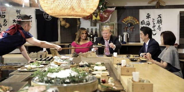 Former President Trump is served a baked potato with butter while sitting at a counter with first lady Melania Trump, Japanese Prime Minister Shinzo Abe and Abe's wife Akie Abe. The pair were photographed often during Trump's multiple trips to the island nation.