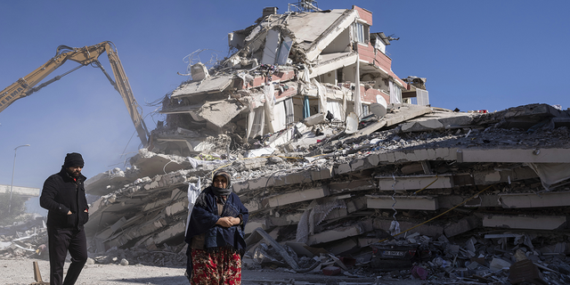 Local residents walk in front of a destroyed building in Nurdagi, southeastern Turkey, on Thursday, Feb. 9.