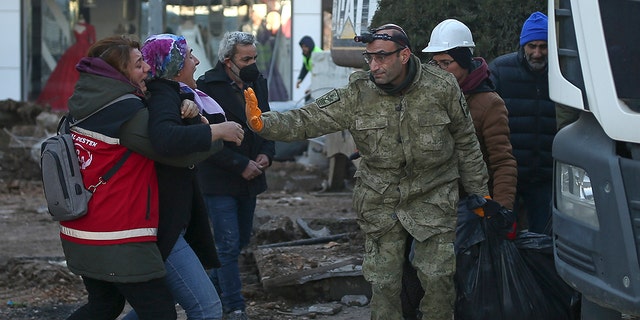 A woman reacts as rescue workers carry the body of an earthquake victim in Adiyaman, southeastern Turkey, Thursday, Feb. 9, 2023.