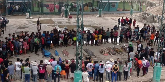 Residents stand around the bodies of persons who perished in recent landslides in Camana, Peru, on Feb. 6, 2023.