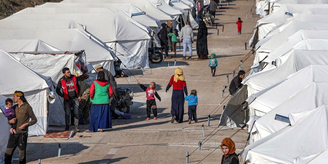 People walk along an alley between tents at a camp for the displaced erected in the aftermath of the February 6 deadly earthquake that hit Syria and Turkey, in Jindayris in northwestern Syria on Feb. 19, 2023.