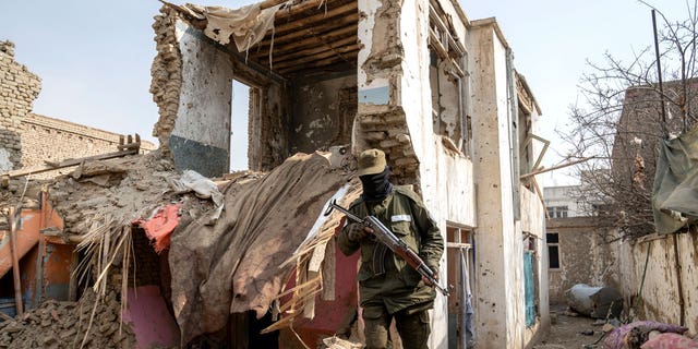 A Taliban fighter checks an Islamic State group house that was destroyed in the ongoing conflict between the two in Kabul, Afghanistan, on Feb. 14, 2023.