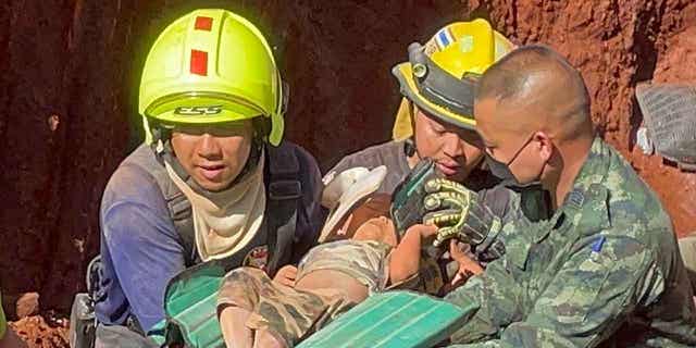 Rescue workers and military carry a child from a deep hole in the province of Tak, Thailand, on Feb. 7, 2023. The toddler fell into the hole used for groundwater pipes yesterday evening. 