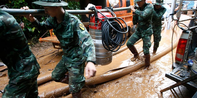 Thai soldiers carry a water pump to drain the cave where 12 boys and their soccer coach had been missing in Mae Sai, Chiang Rai province in northern Thailand.
