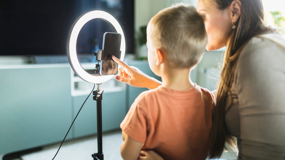 Mother posing young boy in front of phone with ring light