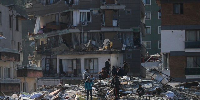 Men walk among the debris of collapsed buildings in Hatay, southern Turkey, Thursday, Feb. 9, 2023. Emergency crews made a series of dramatic rescues in Turkey on Friday, pulling several people, some almost unscathed, from the rubble, four days after a catastrophic earthquake killed more than 20,000. 
