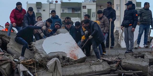 Men search for people among the debris in a destroyed building in Adana, Turkey, Monday, Feb. 6, 2023. A powerful quake has knocked down multiple buildings in southeast Turkey and Syria and many casualties are feared.