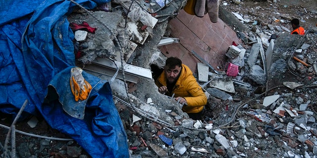 A man searches for people in a destroyed building in Adana, Turkey, Monday, Feb. 6, 2023. A powerful quake has knocked down multiple buildings in southeast Turkey and Syria and many casualties are feared.