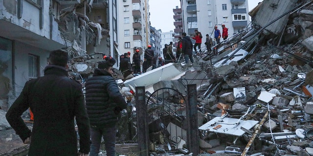 People and rescue teams try to reach trapped residents inside collapsed buildings in Adana, Turkey, on Monday.