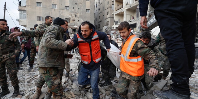 Rescue teams carry a victim from a destroyed building in Aleppo, Syria, Tuesday, Feb. 7, 2023.