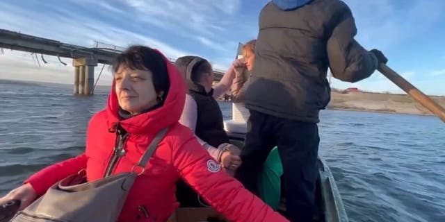 Ukrainian civilians being ferried across a river while escaping Kharkiv.