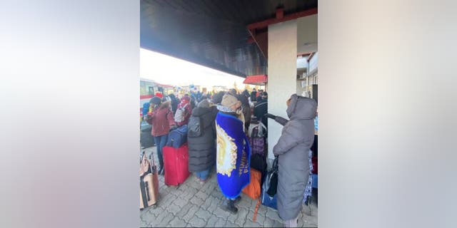 Ukrainians trying to stay warm while waiting to cross the Polish border on foot.