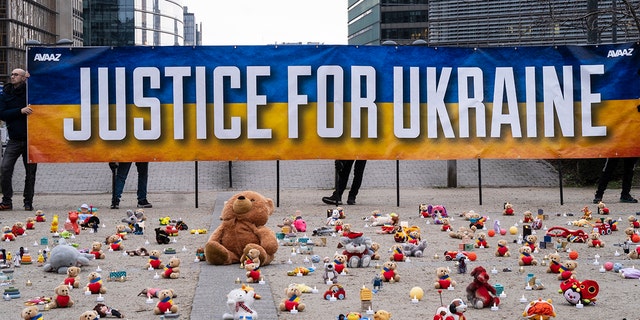 People from U.S.-based nonprofit organization avaaz light candles beside teddy bear in Schuman Roundabout, the heart of the EU district on February 24, 2023 in Brussels, Belgium. 