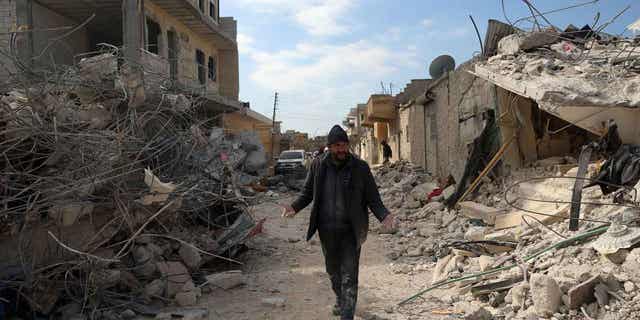 A man walks past collapsed buildings following an earthquake in the town of Jinderis, Syria, on Feb. 14, 2023. The death toll from the earthquakes that struck Turkey and northern Syria is still rising. 