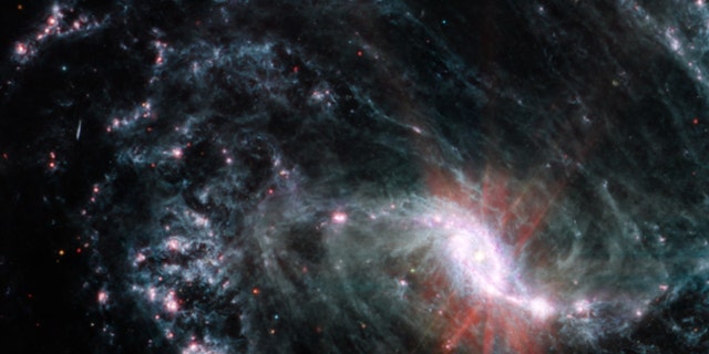 In the MIRI observations of NGC 1365, clumps of dust and gas in the interstellar medium have absorbed the light from forming stars and emitted it back out in the infrared, lighting up an intricate network of cavernous bubbles and filamentary shells influenced by young stars releasing energy into the galaxy’s spiral arms. 
