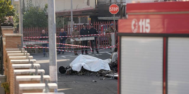 The burned remains of one of the two Italian Air Force aircrafts that crashed in Guidonia on March 7, 2023, is covered with a white cloth. 