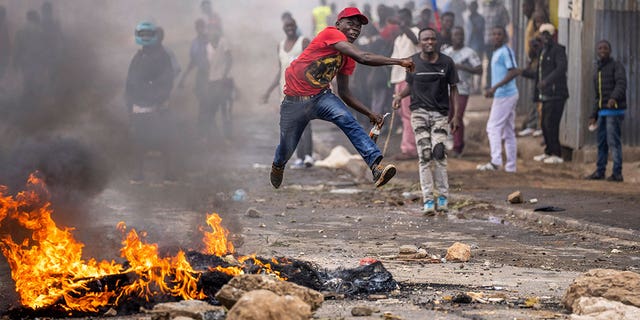 An anti-government protester jumps in the air as he throws a rock towards the police next to a burning barricade in Nairobi, Kenya, on March 20, 2023. 
