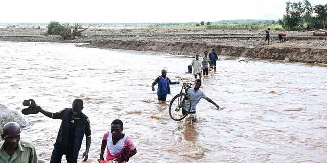 People walk through floodwaters in the aftermath of Tropical Cyclone Freddy in southern Malawi on March 18, 2023. During a conference in the Ethiopian capital of Addis Ababa on March 20, 2023, leaders of African countries discussed finance options that would allow for the forgiveness of debt in exchange for investment in green energies.