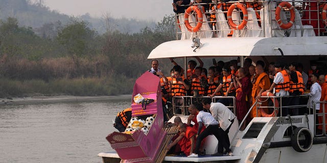 Family members, accompanied by monks and fellow mourners, release the ashes of Duangphet Phromthep in a makeshift boat along with soccer balls and some of his prized possessions into the Mekong River in Thailand on March 6, 2023. 