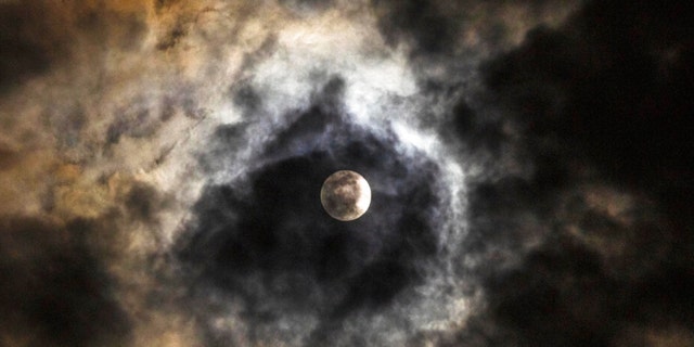 The March full moon, known as the Worm Moon, rises as it hides behind the clouds over the capital Beirut, Lebanon, Tuesday, March 7, 2023. 