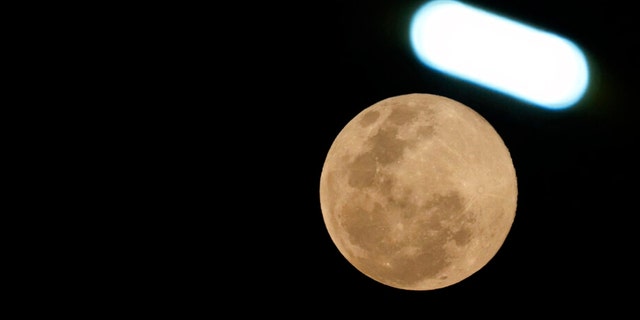 The moon shines under a street lamp in Phnom Penh Cambodia, Tuesday, March 7, 2023. 