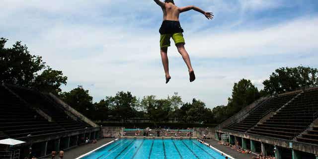 A boy jumps into the water at the Olympic open air public pool in Berlin, Germany, on May 21, 2014. Women in Berlin will be allowed to go topless at the city's public pools soon.