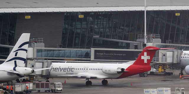 Baggage carts make their way past a Helvetic Airways' aircraft from which about $50 million worth of diamonds were stolen on the tarmac of a Brussels airport on Feb. 19, 2013. The four remaining suspects in the case were acquitted on appeal on March 8, 2023, leaving it unclear whether the mastermind will ever be found. 