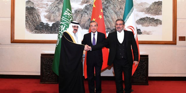 In this photo released by Xinhua News Agency, Ali Shamkhani, the secretary of Iran's Supreme National Security Council, at right, shakes hands with Saudi national security adviser Musaad bin Mohammed al-Aiban, at left, as Wang Yi, China's most senior diplomat, looks on, at center, for a photo during a closed meeting held in Beijing, Saturday, March 11, 2023.