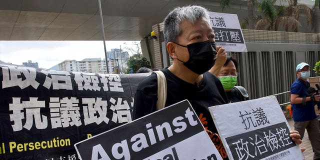 Pro-democracy activist Lee Cheuk-yan, center, holds placards as he arrives at a court in Hong Kong on April 1, 2021. Hong Kong national security police arrested March 9, 2023, Lee Cheuk-yan's wife Elizabeth Tang, a veteran labor activist.